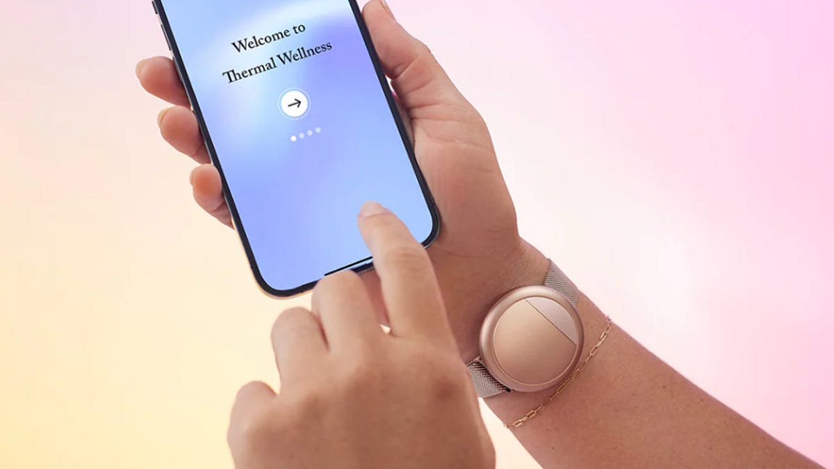 An Embr Wave device on a wrist with a hand holding a phone