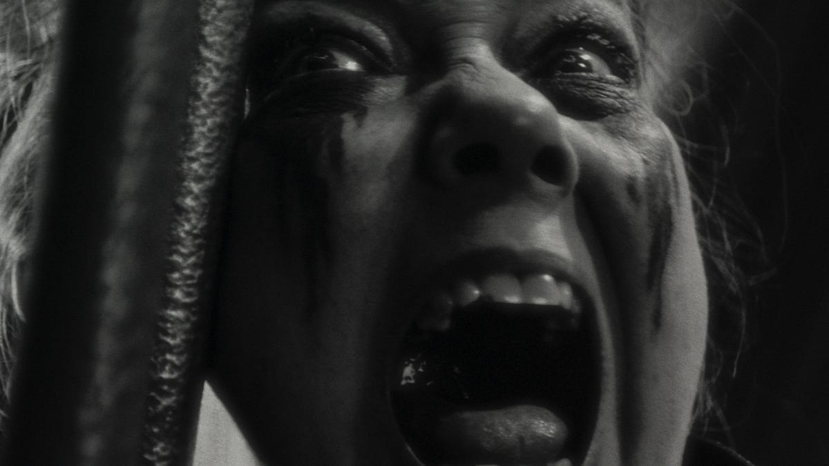 A close-up of a woman screaming in black and white.