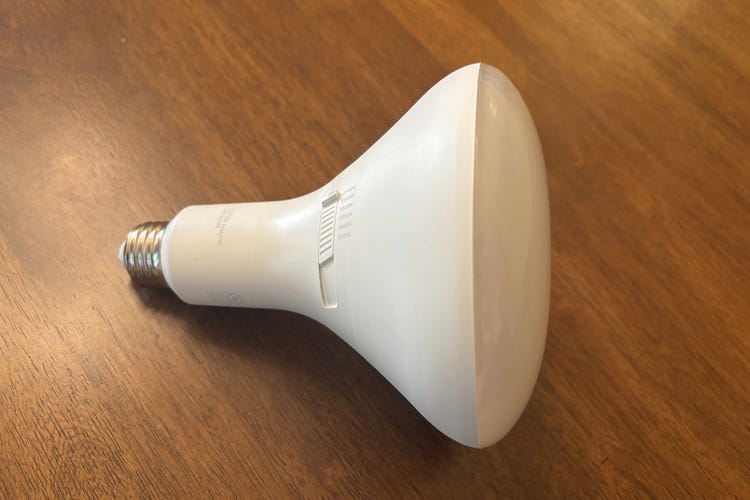An Ecosmart dimmable bulb against a wood surface.