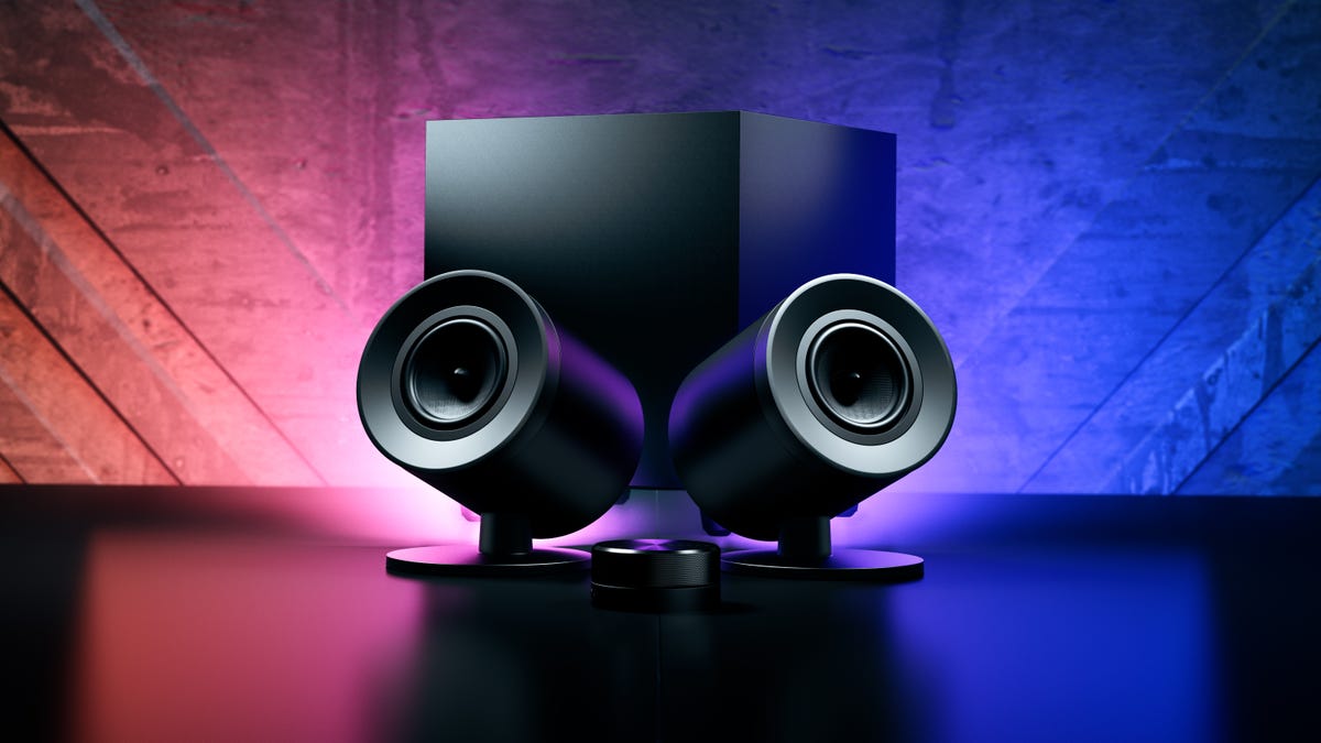 Razer Nommo V2 Pro stylized images with the can-shaped satellites in front of the subwoofer with black and red uplighting