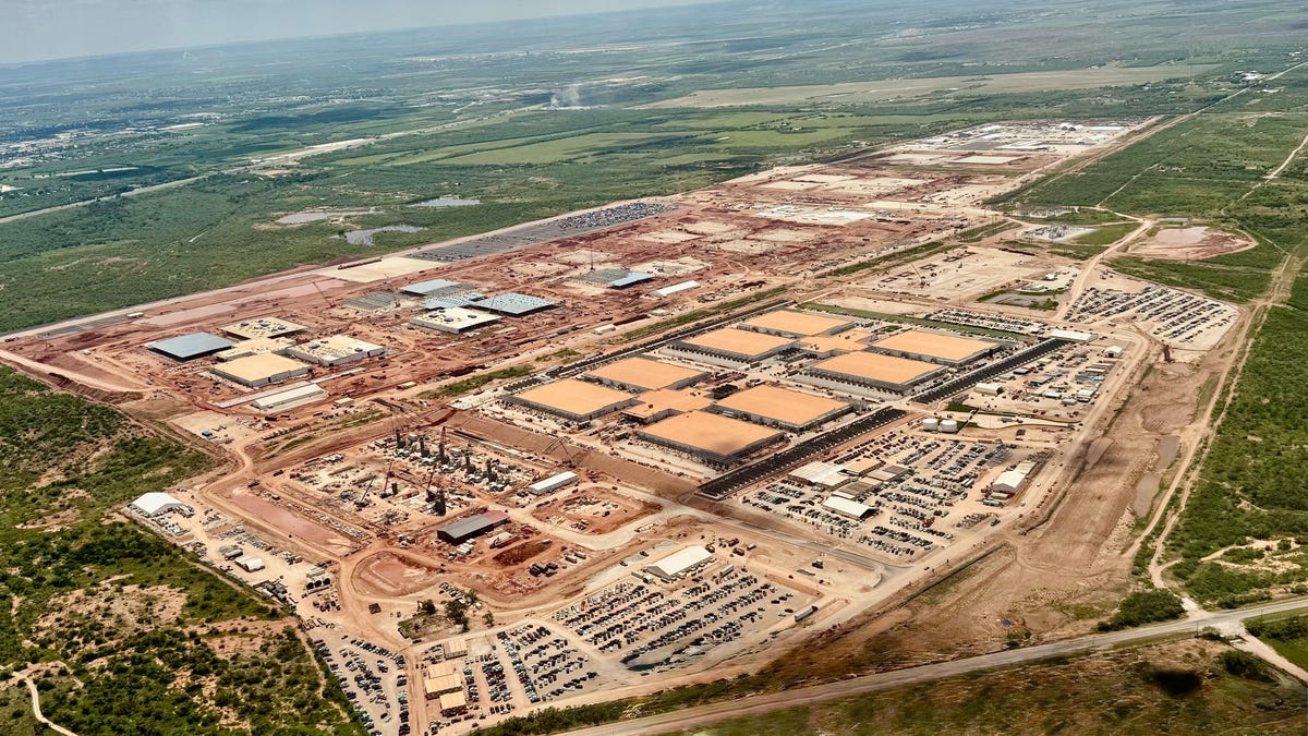 Aerial view of a sprawling data center facility under construction, with wide open West Texas landscape in the background