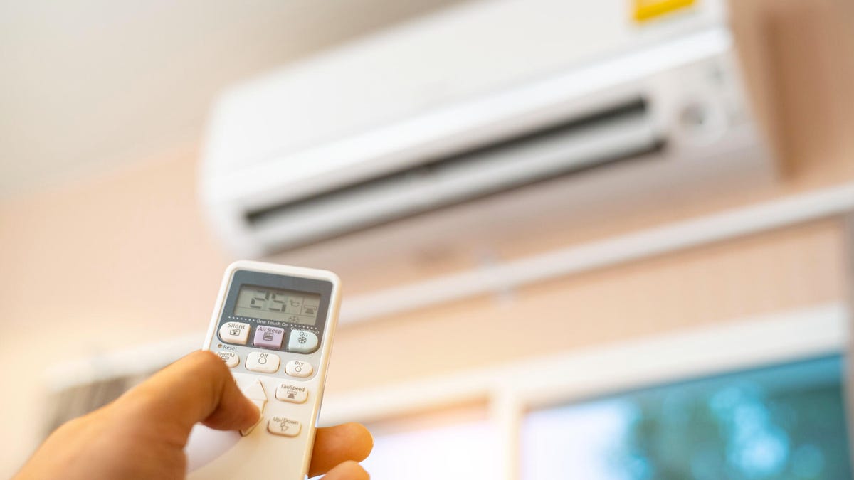 Person using remote to turn on air conditioner.