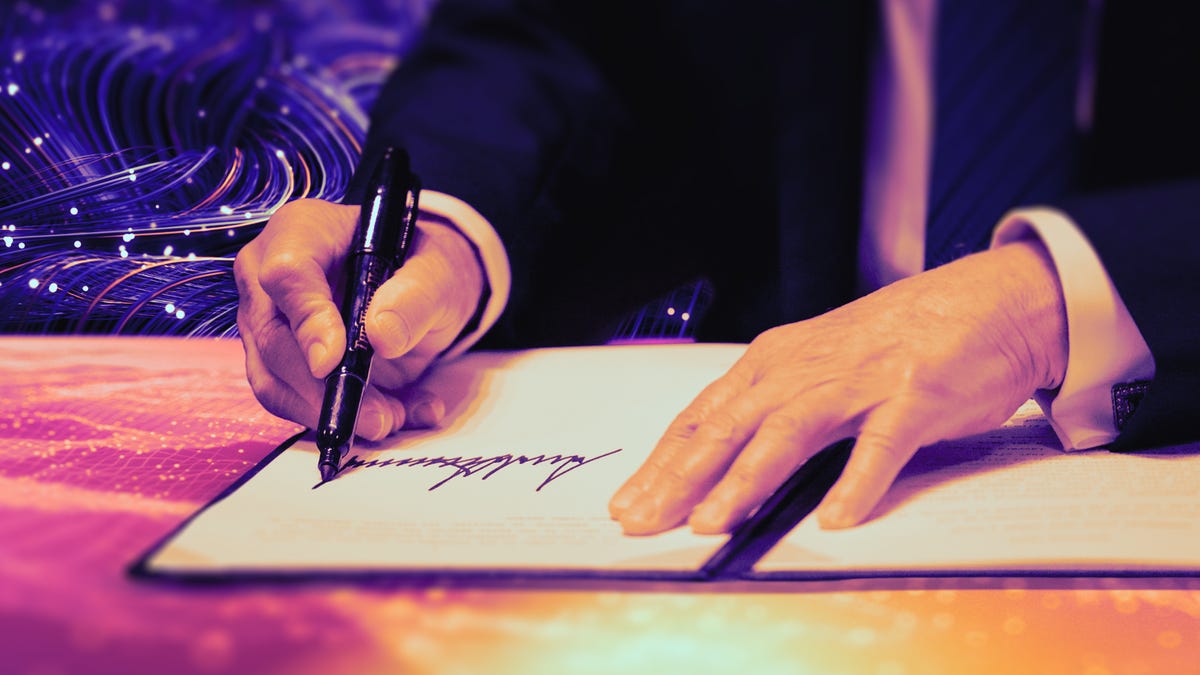 A suited man signs an official document on a desk with digital swirls in the background.