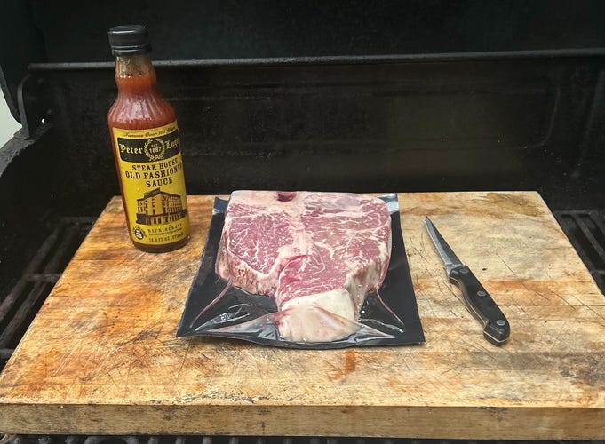 steak on cutting board with bottle of luger sauce