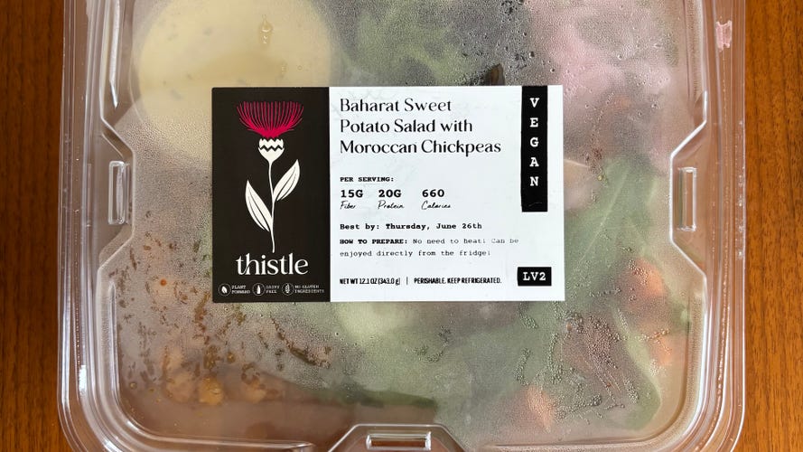 Thistle Sweet Potato Salad in plastic packaging on wood table.