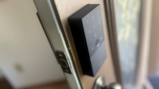 The Aqara U100 lock, showing the keypad on an ajar brown door.