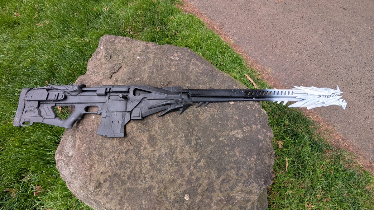 A black and white sniper rifle prop on a rock