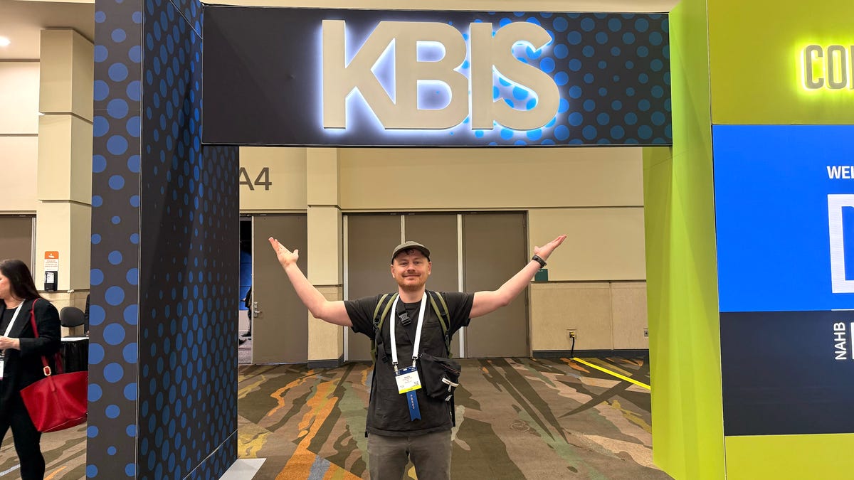 person standing under KBIS sign.