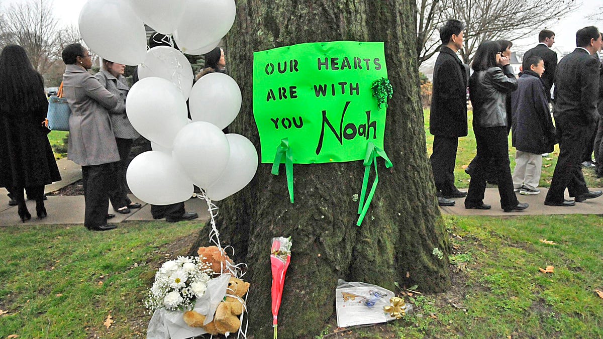 On December 12, 2012, a green poster on a tree memorializes Noah Pozner, a 6-year-old killed in the Sandy Hook school shooting.