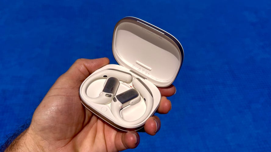 The Shokz OpenFit Pro in their case held over a pool of water