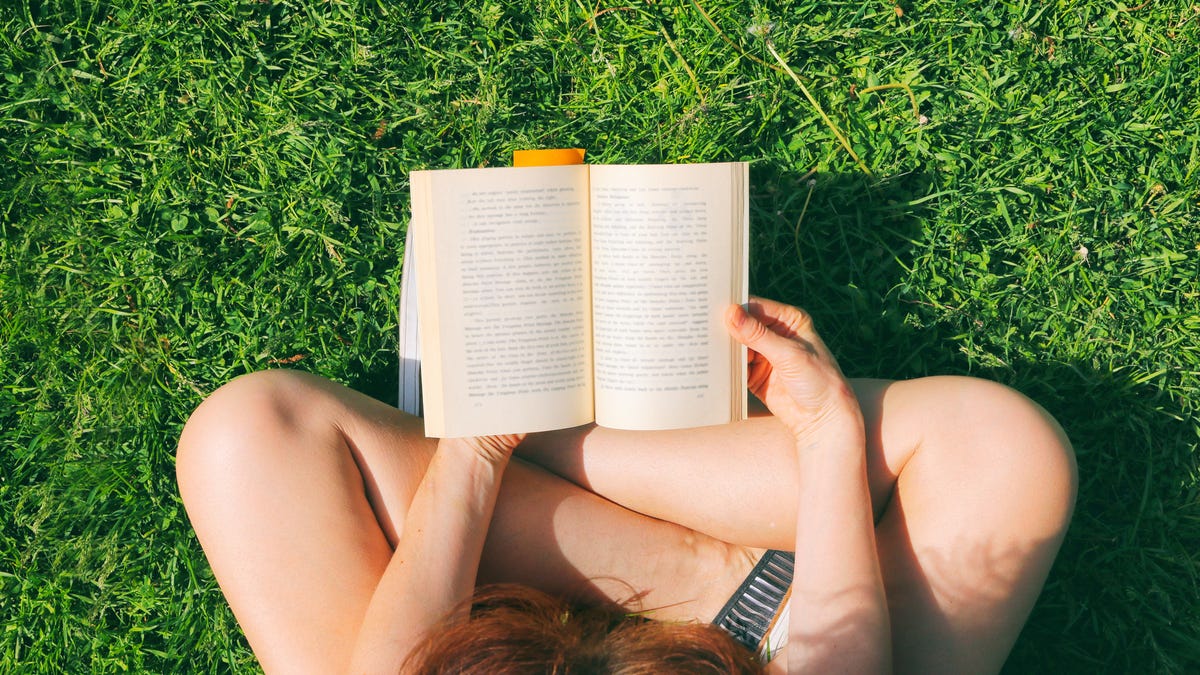 Top view of someone reading a book in the summer park