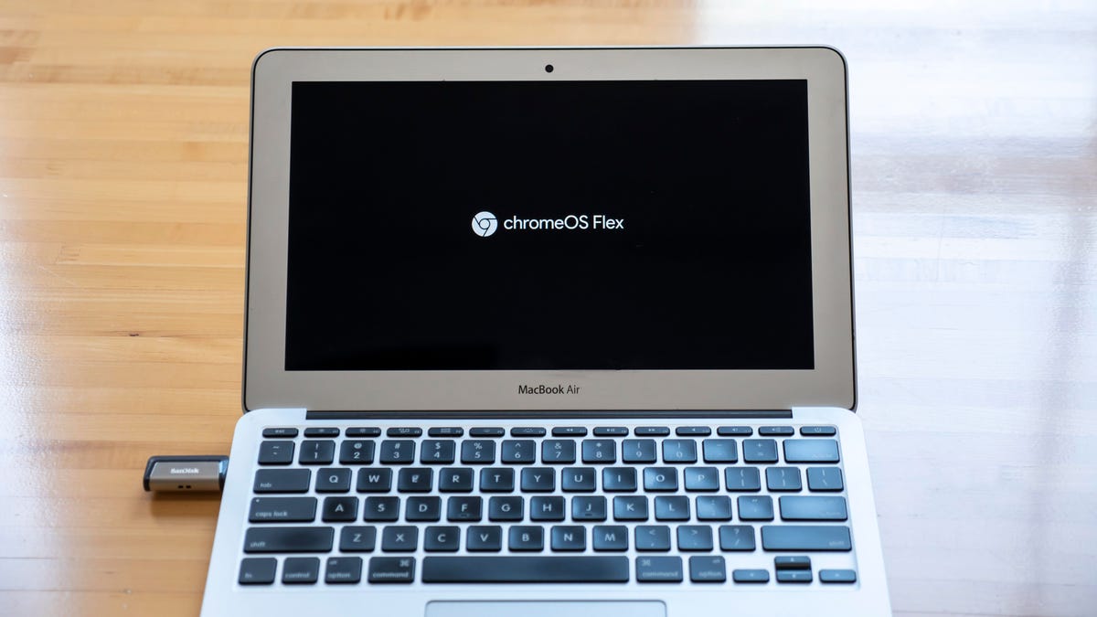 A MacBook Air on a desk open and displaying the splash screen for ChromeOS Flex.
