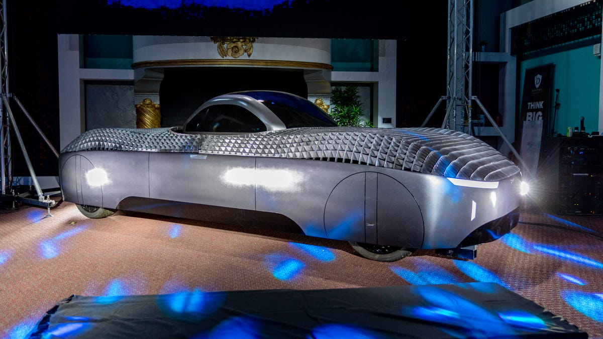 A, sleek dark gray flying car prototype is topped with with an aerodynamic dome for passengers