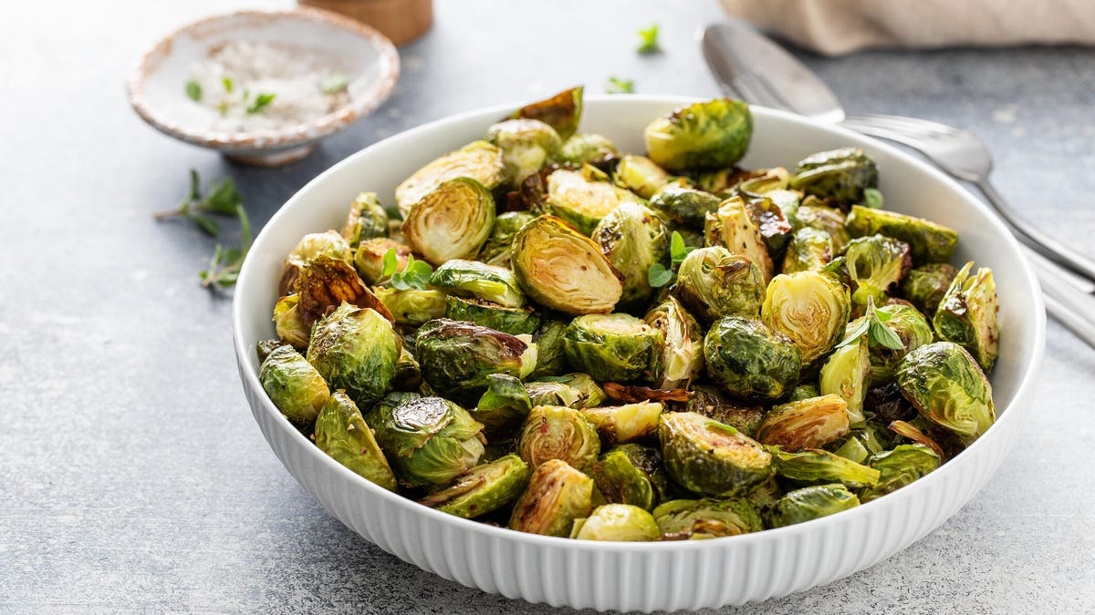 Crispy roasted or air fried brussel sprouts with honey dressing in a white bowl.