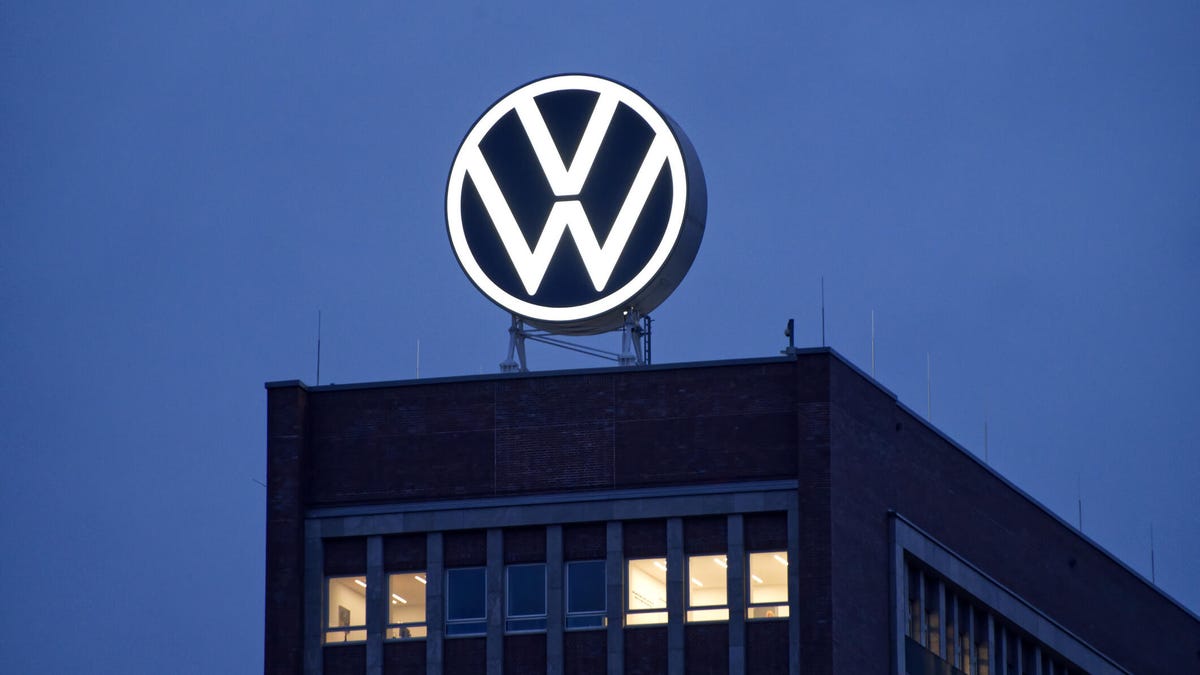 A lit up VW sign is shown on a building against a dark-blue sky.