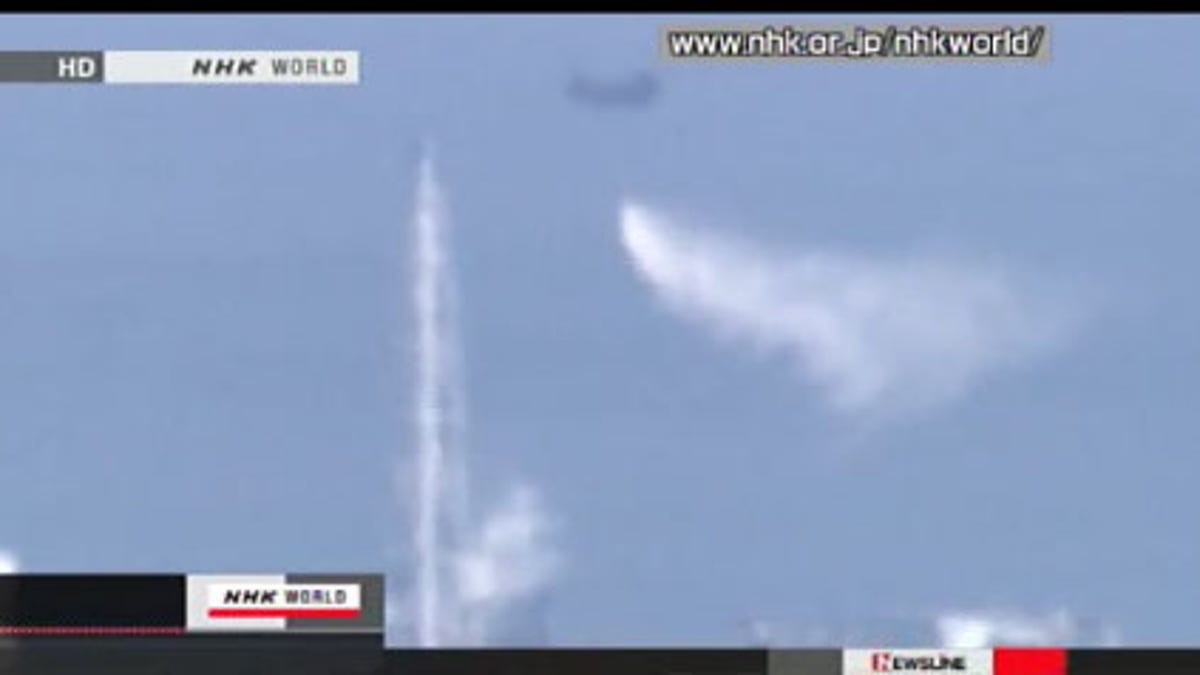 This view from Japan state broadcaster NHK shows a Japanese Special Defense Force helicopter dropping water on reactor 3 at the Fukushima Daiichi nuclear power plant Thursday. The reactor is the smaller steam-emitting building to the right of the tower; the helicopter is at top center dropping the water.