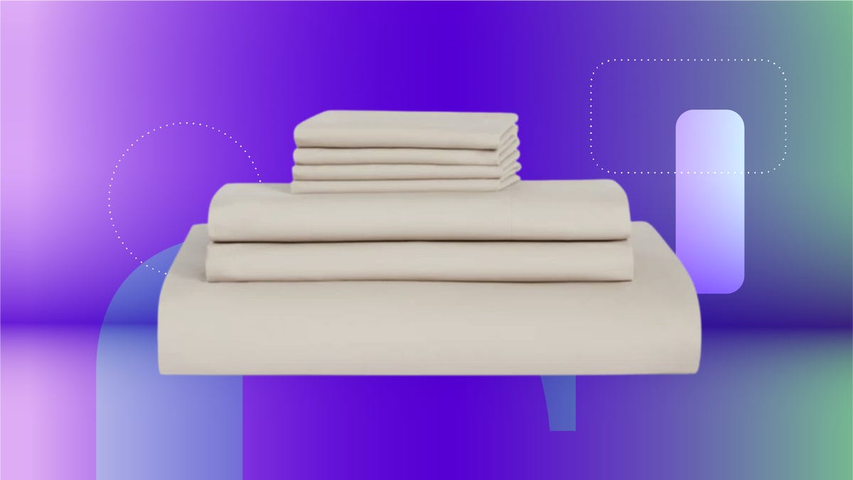 Stacked blue pillows and folded sheets with a white comforter in front on CNET background