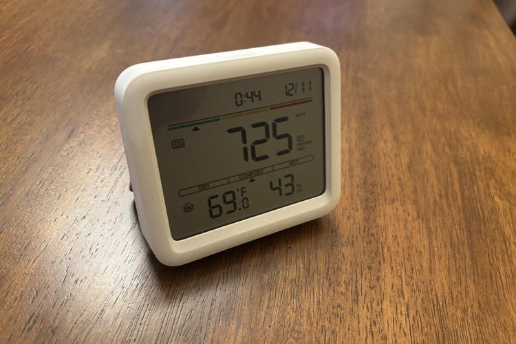 An air monitor from Switchbot showing air quality on a wood table.