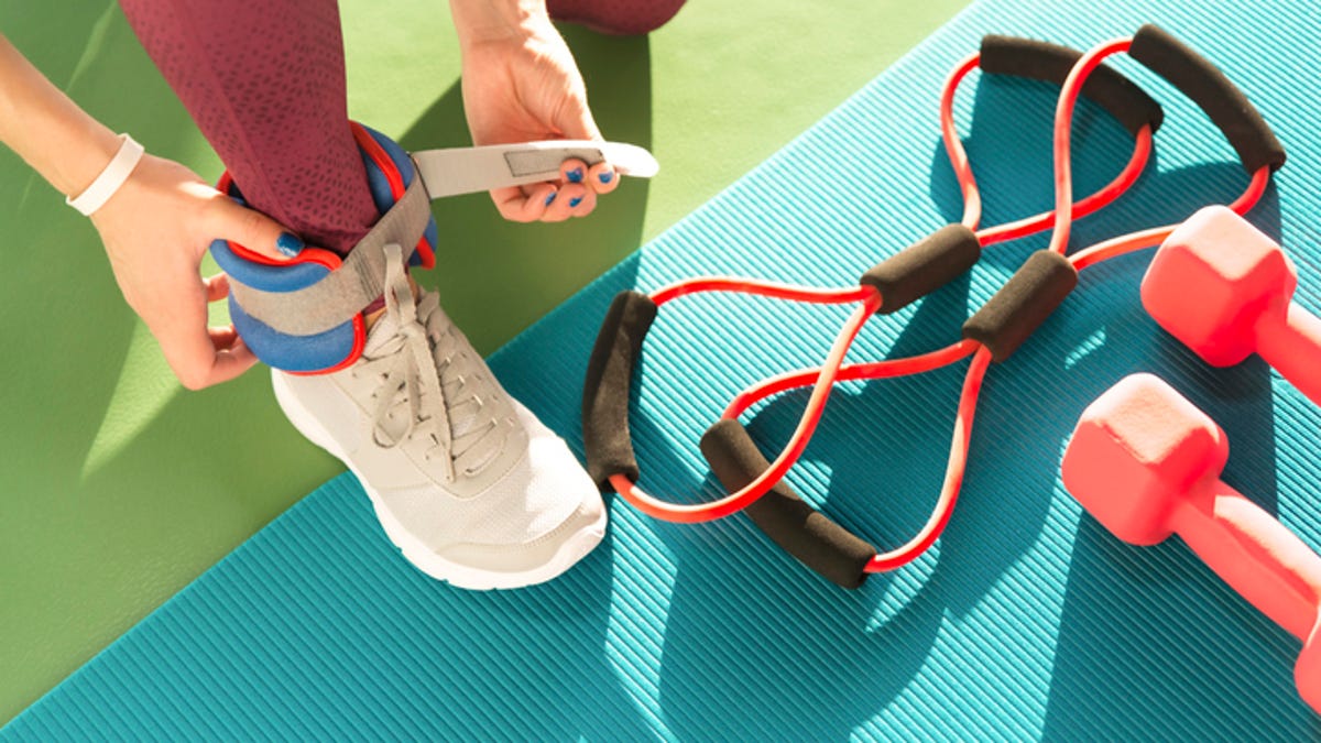 A woman straps on an ankle weight