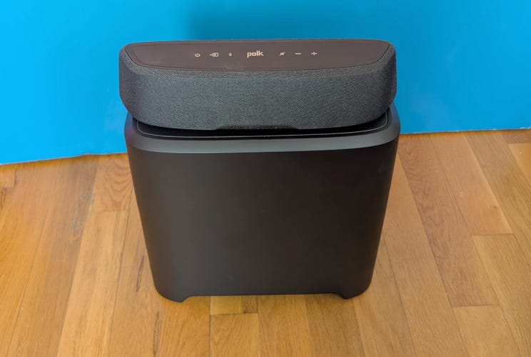 The Polk soundbar sitting on top of the subwoofer against a blue background