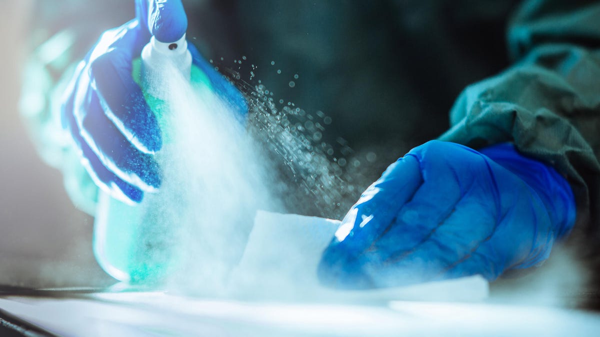 A person spraying disinfectant onto a surface