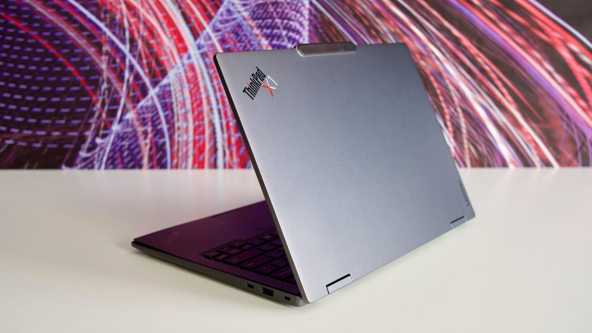Lenovo ThinkPad X1 Carbon Gen 14 Aura Edition laptop sits on a table in front of a multicolored background.