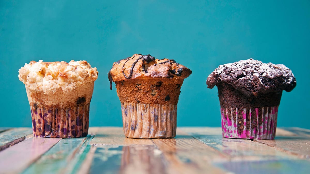 three muffins sitting on a wooden table top