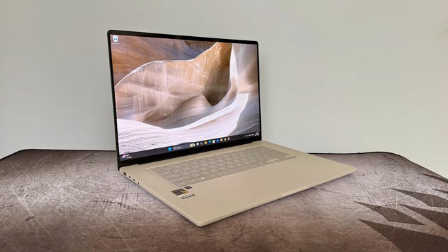 A beige-colored Asus Zenbook A16 laptop sits on a brown surface. The A16 is open and turned on.