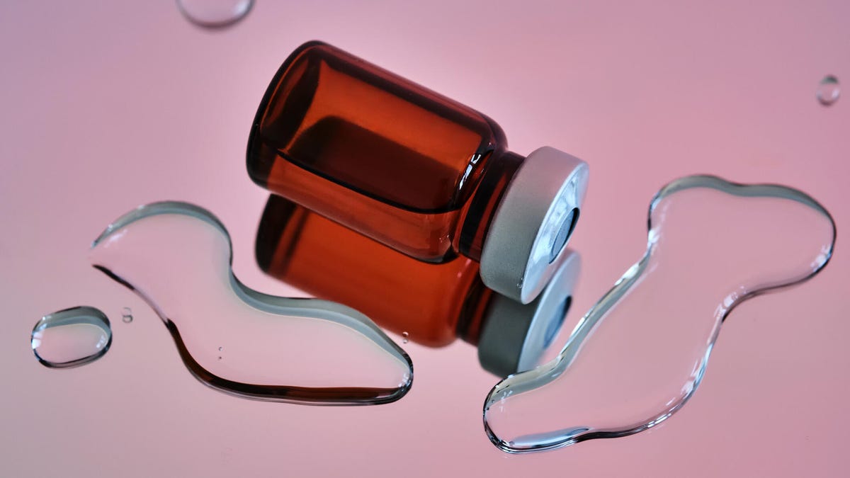 A vial of medicine against a light pink background
