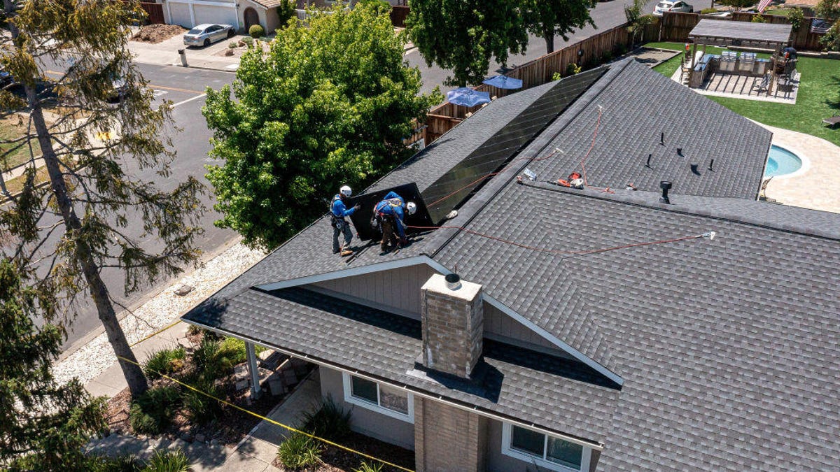 Workers install solar panels on a home in California.