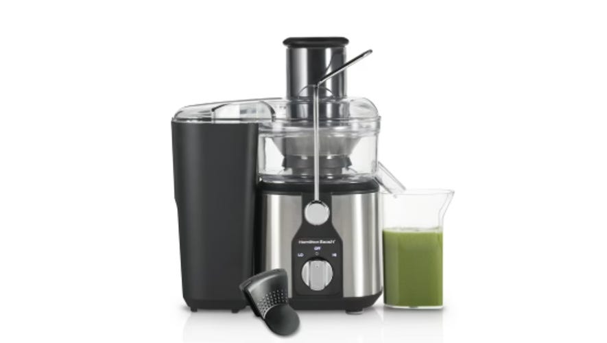 a black and silver juicer with a green juice next to it