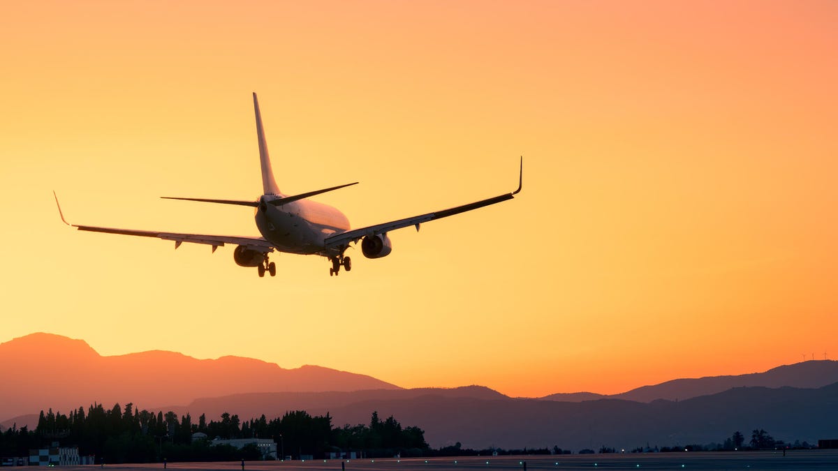 Amidst a breathtaking sunset, an airplane lands gracefully, offering a sense of adventure and escape.