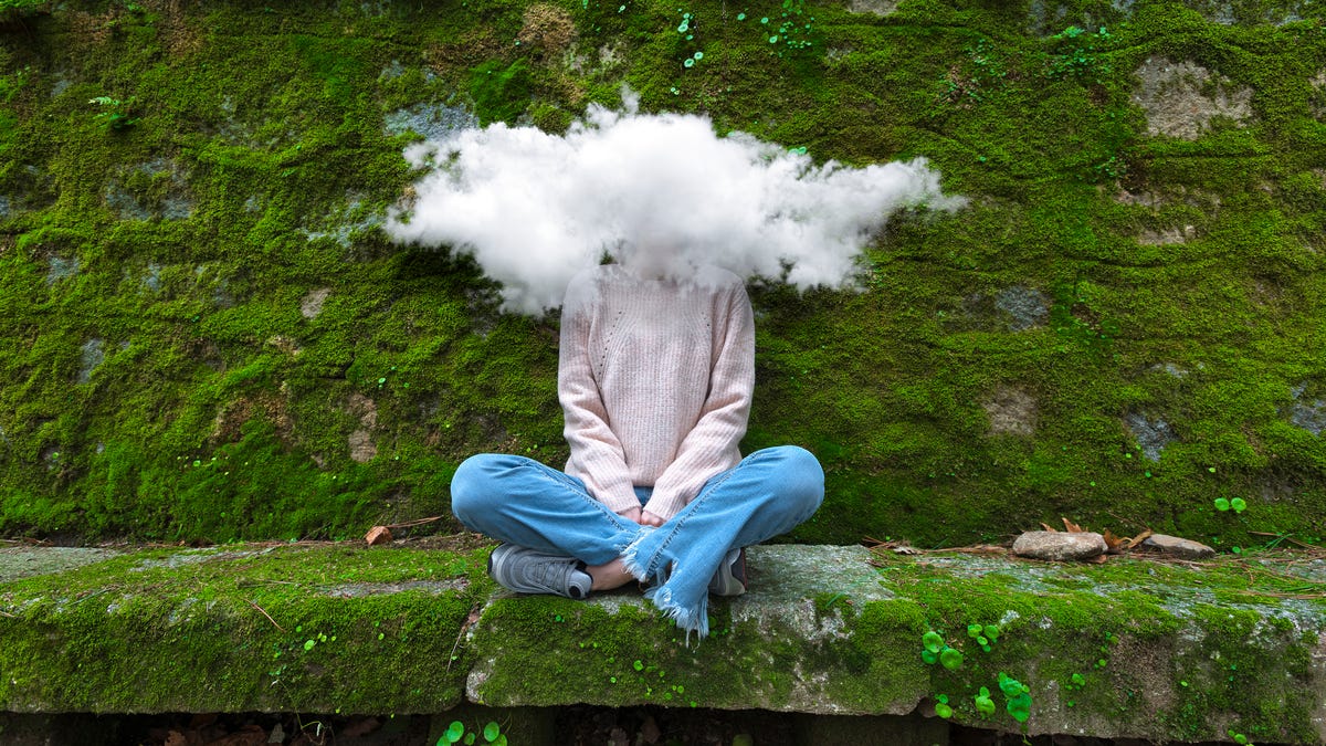 Woman sitting on a bench with a cloud on her head