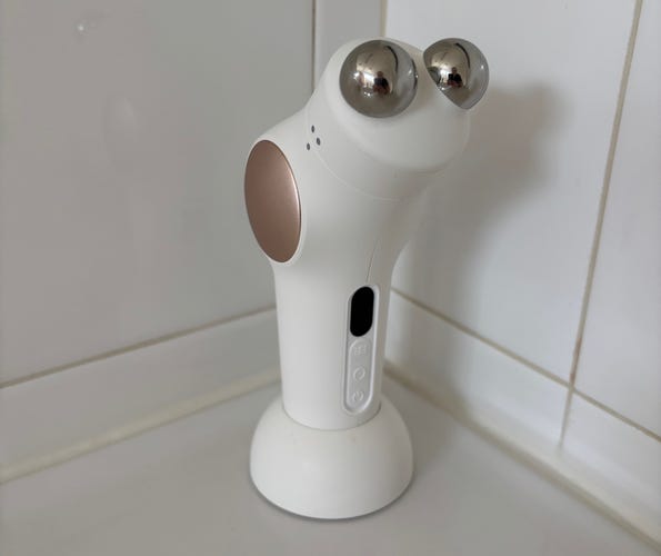 The white and rose gold Theraface pro in its stand on a white countertip.