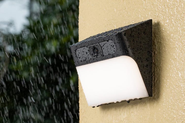 Eufy's solar light cam on an orange stucco wall.