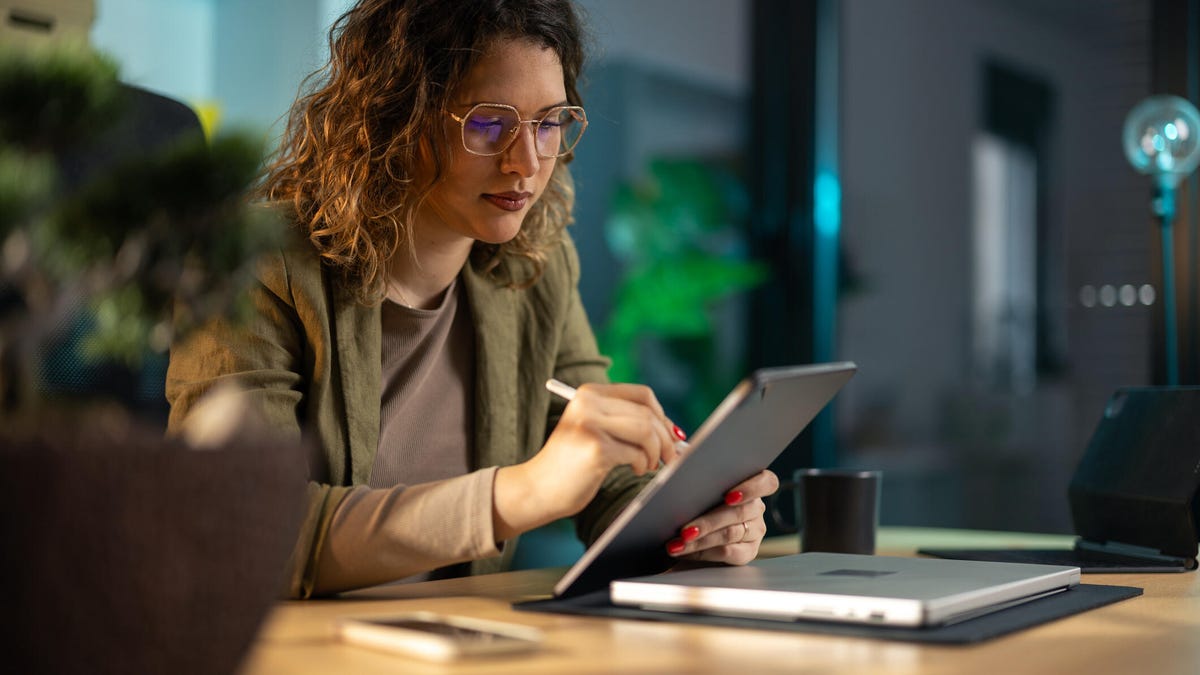 An image of a woman writing on a tablet gettyimages-2142489831