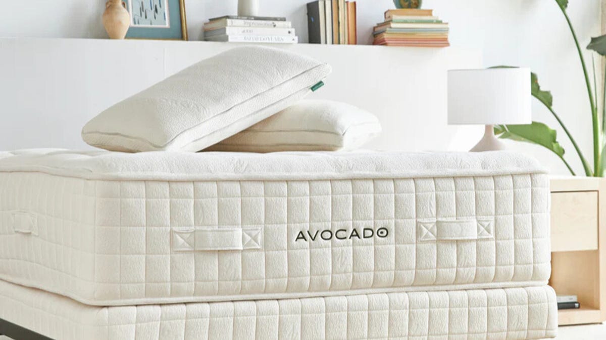 Avocado mattress and pillow on bed base against headboard.