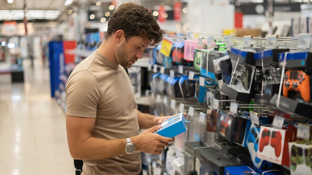 A man in a store looks down at a game accessory he is holding.