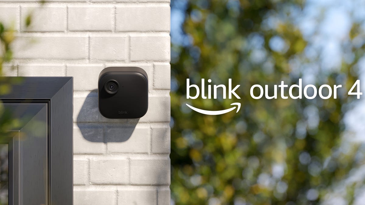 small black security camera on white brick wall, name to the right of it