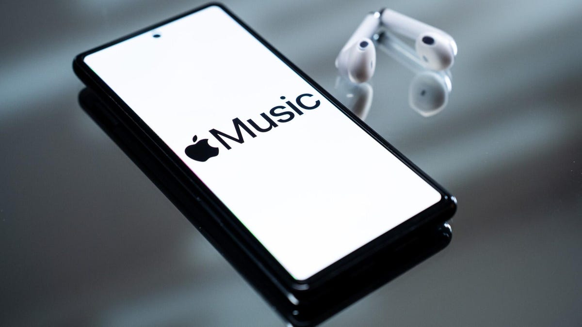 An image of a smart phone with the Apple Music logo in black text on a white background sitting next to a pair of white airpods.