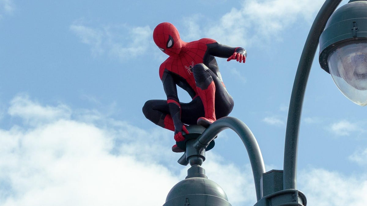Spider-Man crouches on the top of a streetlamp.