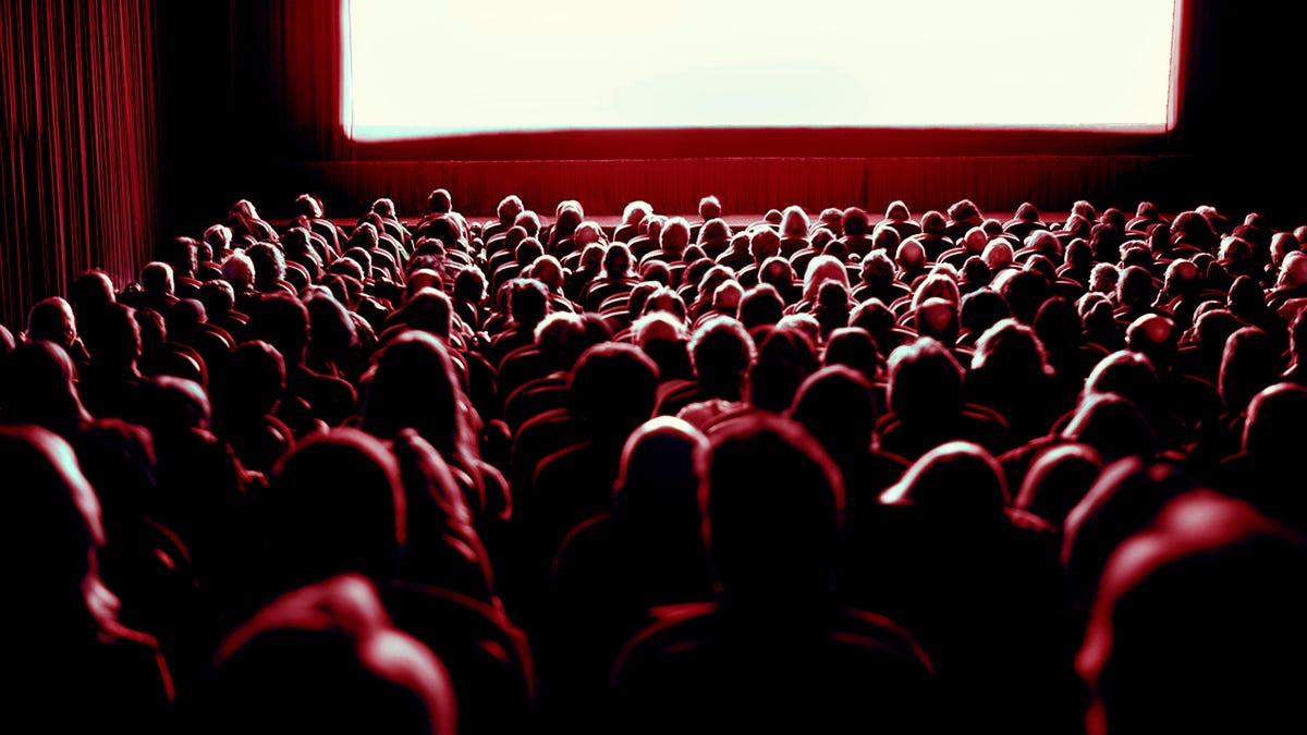 Crowd watching movie in theatre, rear view