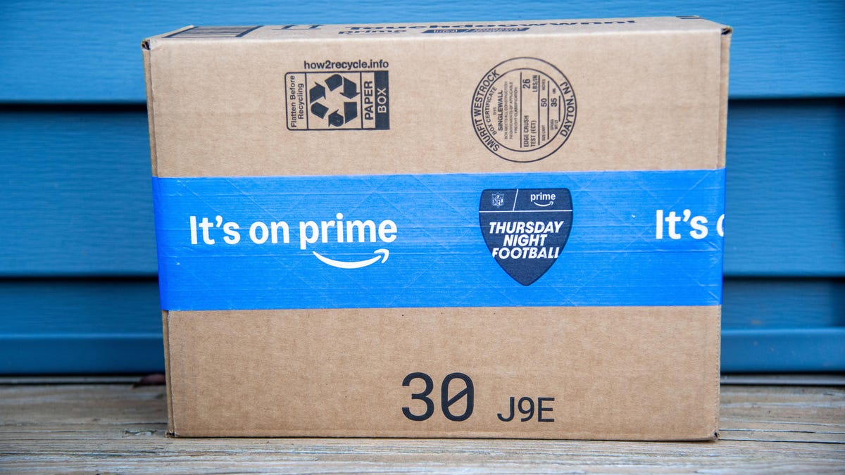 an Amazon delivery box with a blue sealing tape reading It's on prime with the Amazon Prime logo