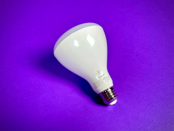 The BR30 floodlight version of the GE Cync Reveal Smart Bulb against a purple background.