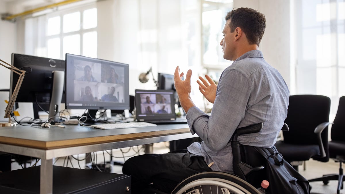 Man in wheelchair using videoconferencing on computer