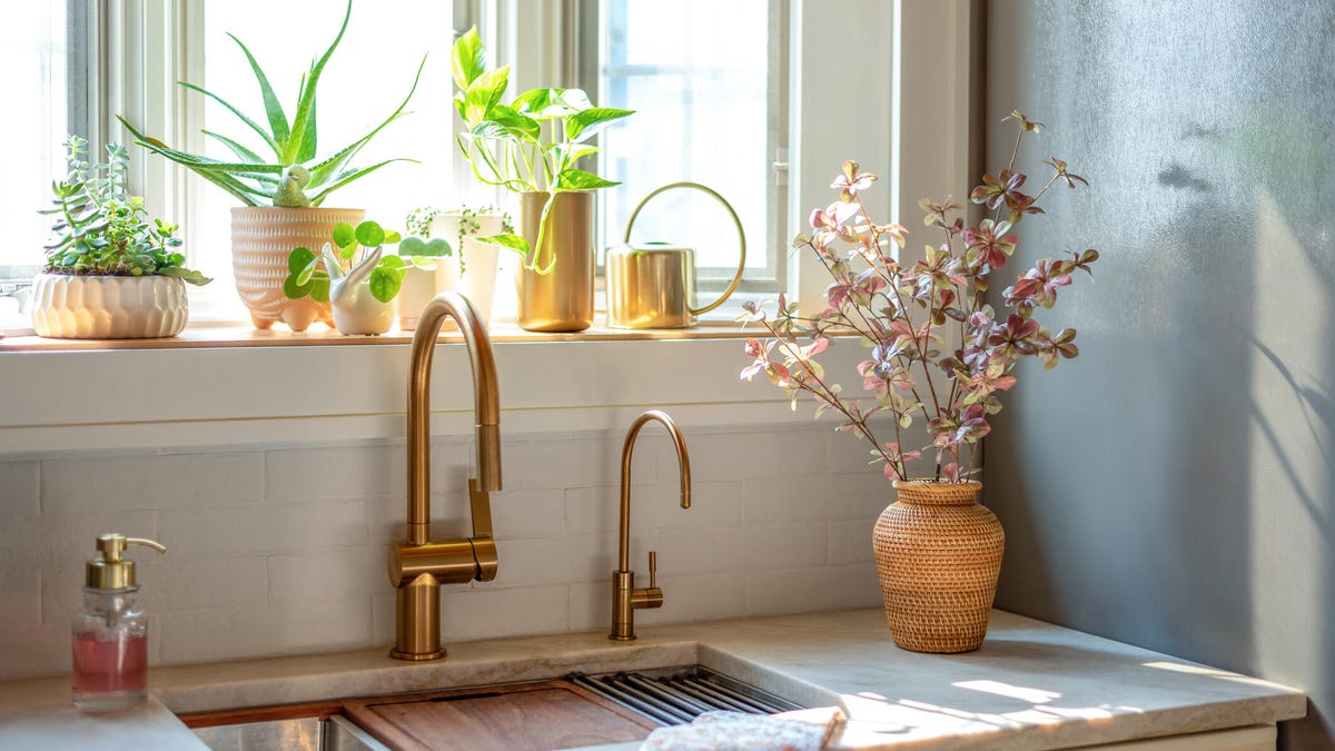 Workstation sink with gold faucets in a stylish light and bright kitchen