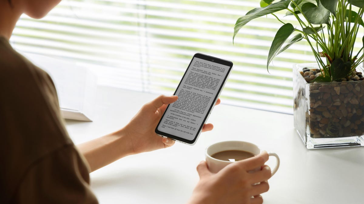 TCL NxtPaper phone held with coffee