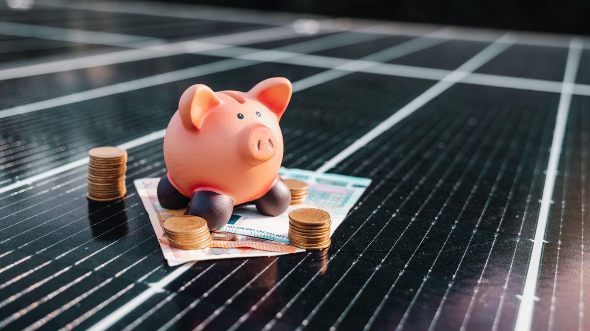 A piggy bank sits on a solar panel