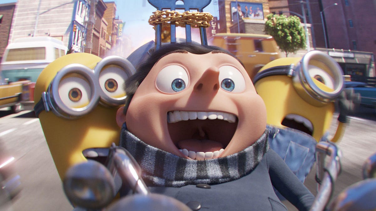 Young Gru and two Minions race along a street on a motorcycle