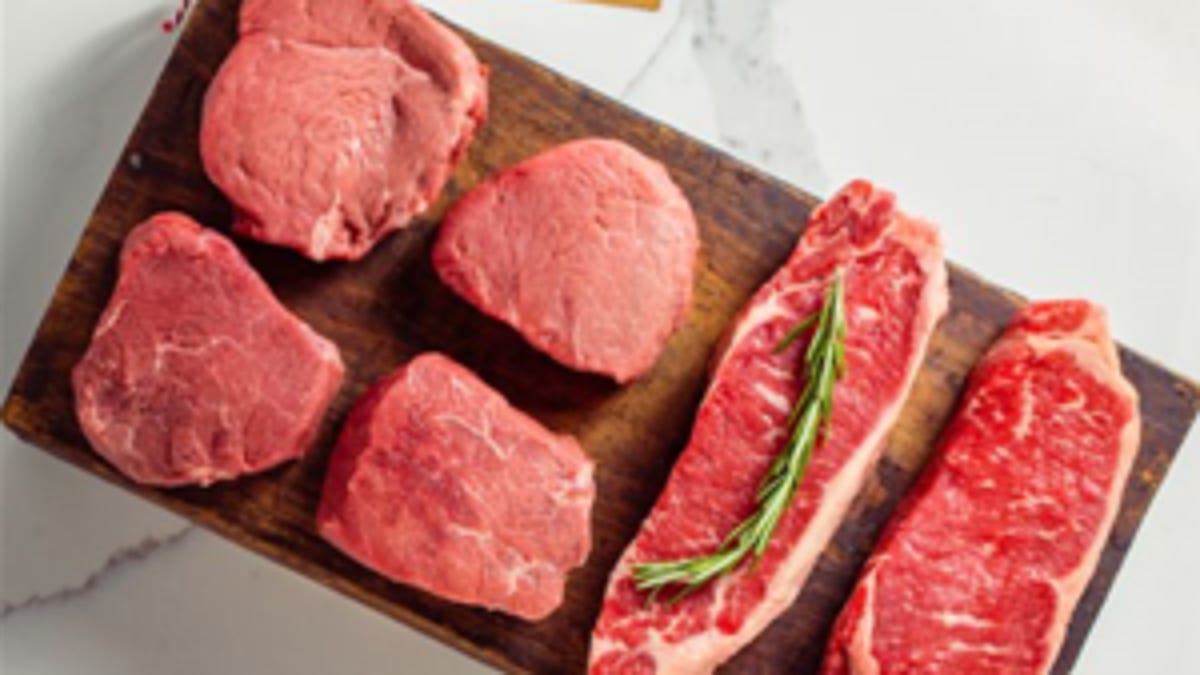 four raw filets and two strip steaks rest on a cutting board